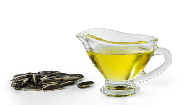 Sunflower oil in a glass gravy boat and a handful of sunflower seeds isolated on a white background.
