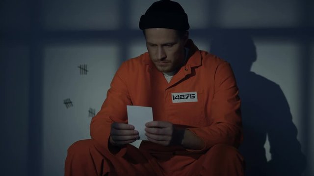 Depressed caucasian prisoner kissing photo, missing beloved, serving sentence