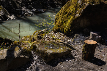 Fototapeta premium Huge fairy stones (boulders) covered with green moss are among the trees in the forest next to the mountain river