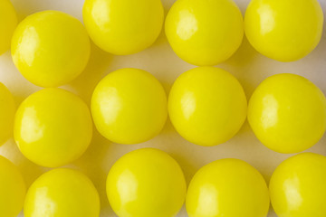 Vitamin C in the form of yellow round dragees on a light background close-up. The image is suitable for the subject of health, prevention of beriberi and related topics.