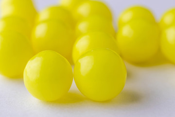 Vitamin C in the form of yellow round dragees on a light background close-up. The image is suitable for the subject of health, prevention of beriberi and related topics.
