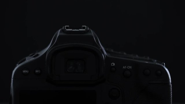 Modern DSLR camera against black background illuminated with soft moving light