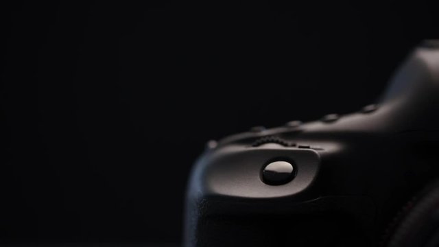 Modern DSLR camera against black background illuminated with soft moving light