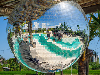 Disco ball reflecting green swimming pool. Bali.
