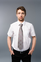 serious businessman posing with hands in pockets on grey background