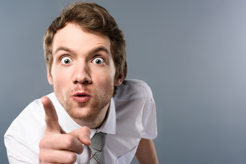aggressive businessman with funny face expression pointing with finger at camera