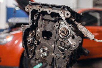 Selective focus. Engine Block on a repair stand with Piston and Connecting Rod of Automotive technology. Blurred car on background. Interior of a car repair shop.