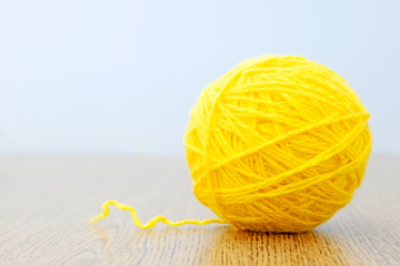 Yellow ball of thread on a light background. Craft or knitting concept. The idea of solving the...