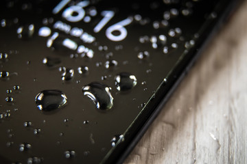 Front side of waterproof smartphone covered with drops of water