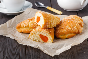Biscuit rolls filled with jam with powdered sugar on top on plate over wooden table
