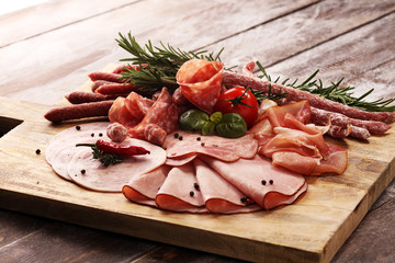 Food tray with delicious salami, pieces of sliced ham, sausage and salad. Meat platter selection.