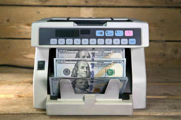 electronic money counter machine is counting is counting the American hundred-dollar (US dollars)...
