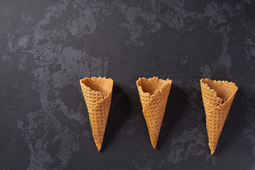 Three sweet wafer cones on a black background.