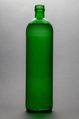 green glass bottle of water isolated on gray background