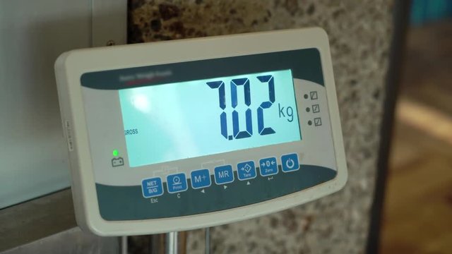 Passenger checking luggage weight with scale in airport