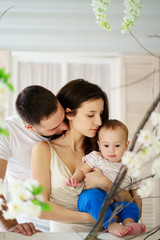 Obraz premium Parents hugging and kissing their baby son