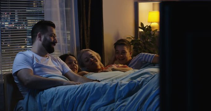 Family watching TV from bed