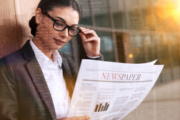 businesswoman reading newspaper outside of office buildings