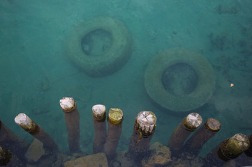 Two rubber tires in a clear water of a turquoise lake. Bird view from a pier of tires thrown in a lake. © Josif