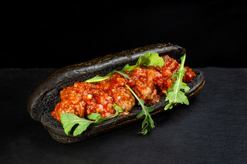 Black hot dog bun with minced meat.