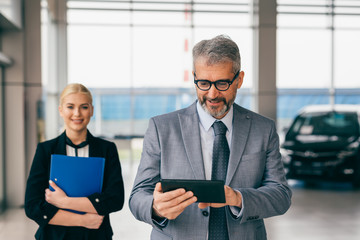 confident manager and saleswoman in car dealership showroom