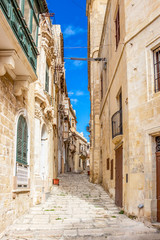 Fototapeta na wymiar Beautiful narrow lane with typical Maltese architecture in Cospicua - one of the Three fortified Cities of Malta