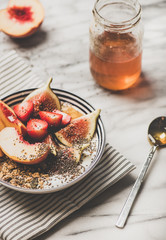 Healthy summer breakfast set. Greek yogurt granola bowl with strawberry, figs, peach, chia seeds and honey over white marble background. Vegetarian, dieting, detox food concept