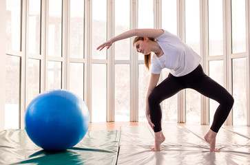 Girl practice with exercise ball. Stretch exercise, standing on her toes. Yoga concept. Pilates