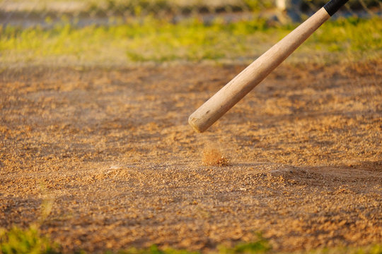 Baseball bat hitting home plate on ball field in park.