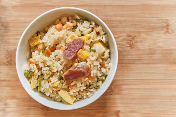 A Bowl of Chinese Fried Rice with Pork Sausages and vegetables.
