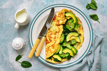 Omelette stuffed with green vegetables : broccoli, avocado and baby spinach.Top view with copy space.