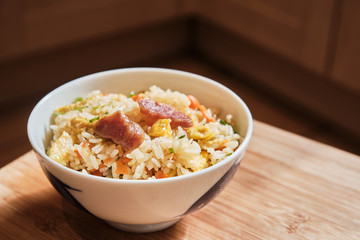 A Bowl of Chinese Fried Rice with Pork Sausages and vegetables.