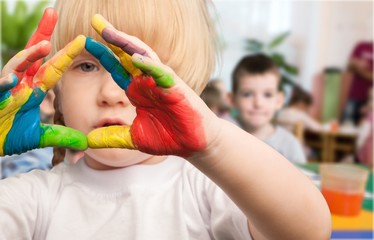 Obraz premium Cute little girl with colorful painted hands on class background