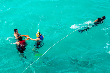 Leisure and sports, several people snorkeling in the blue sea