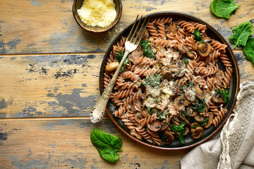 Whole wheat fusilli pasta with mushroom and spinach.Top view with copy space. - obrazy, fototapety, plakaty