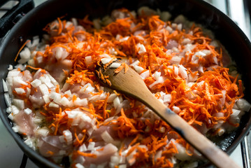Cooking for soup, chopped carrots and onions are fried in a pan
