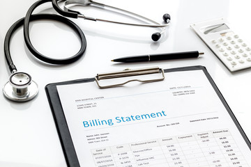 medical treatment bill, calculator and phonendoscope on white background