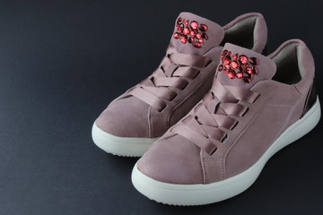 Pink sneakers with jewelry stones on black background