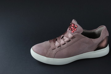 Pink sneakers with jewelry stones on black background