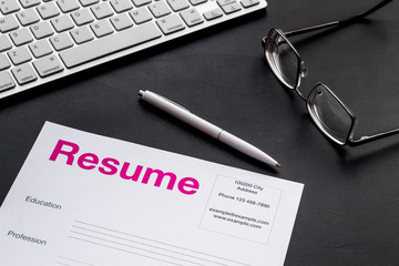Review resumes of applicants set with keyboard and glasses black work desk background