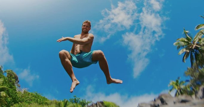 Action camera shot of young man jumping into pristine blue water