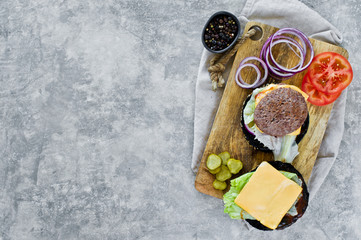 Ingredients for cooking a hamburger on a wooden chopping Board. Top view, gray background, space for text.