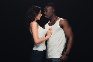 beautiful sensual interracial couple in white tank tops isolated on black