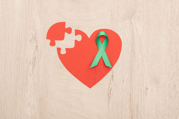 top view of bright paper heart and green ribbon on wooden background