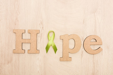 top view of wooden word hope and green ribbon on wooden background