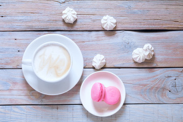 Tasty sweet pink macarons and coffee cup. Macaroons on white background table. Flat lay, top view, copy space