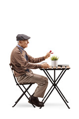 Senior man sitting at a cafe and holding a ring in a box