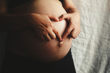Pregnant woman at 9th Month showing heart with hands