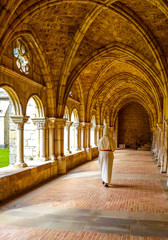 Inner cloister of an abbey with a monk walking and praying