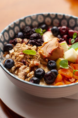 Rich oatmeal with fresh berries, nuts, fruit and peanut butter